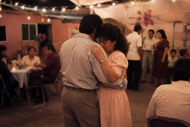 Pareja anónima bailando lentamente en una fiesta familiar con luces cálidas